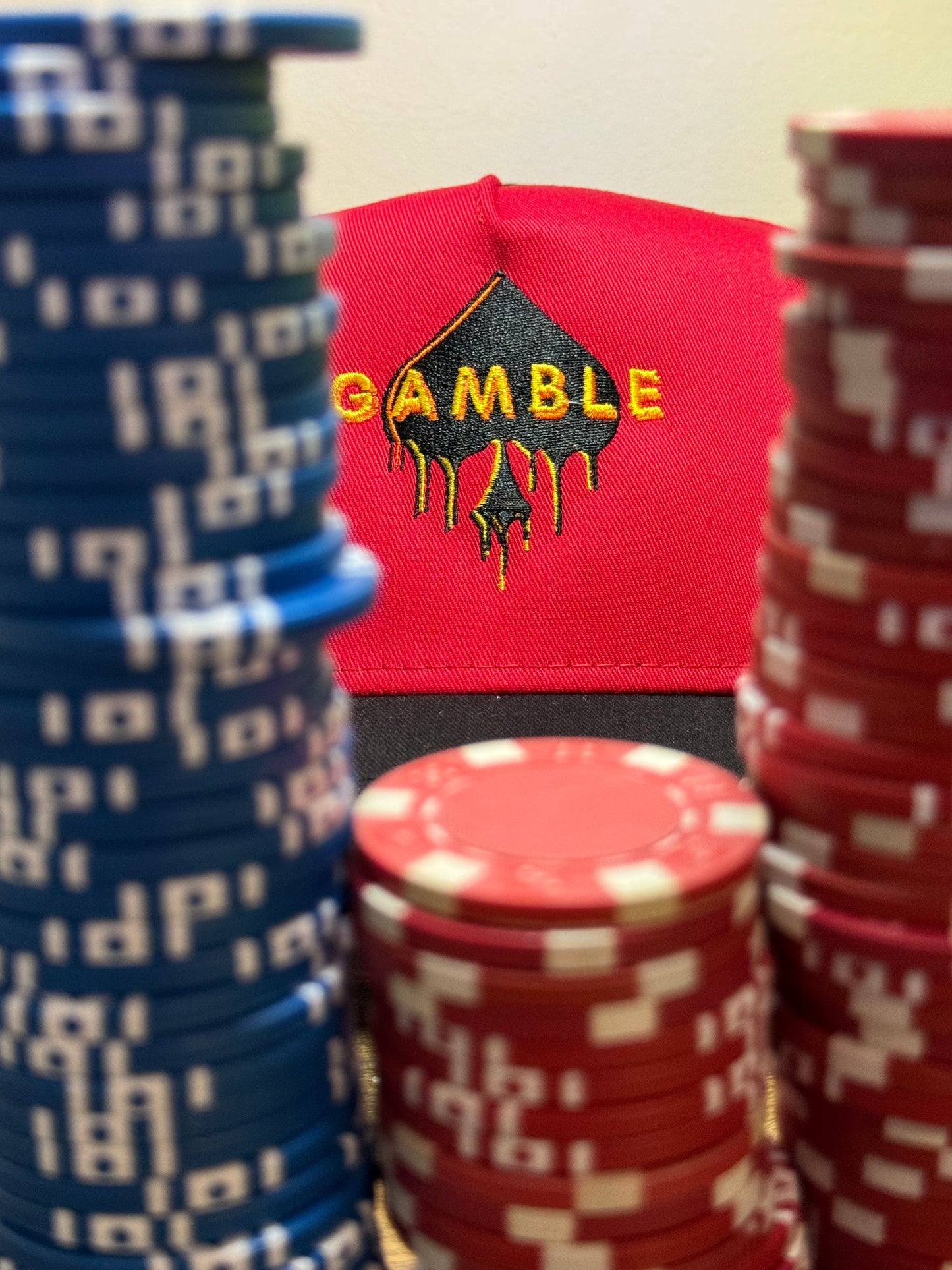Red poker snapback hat with an embroidered ‘Gamble Drip’ design in bold lettering. Structured fit with an adjustable snapback closure. Perfect for poker players who embrace high stakes and bold moves.