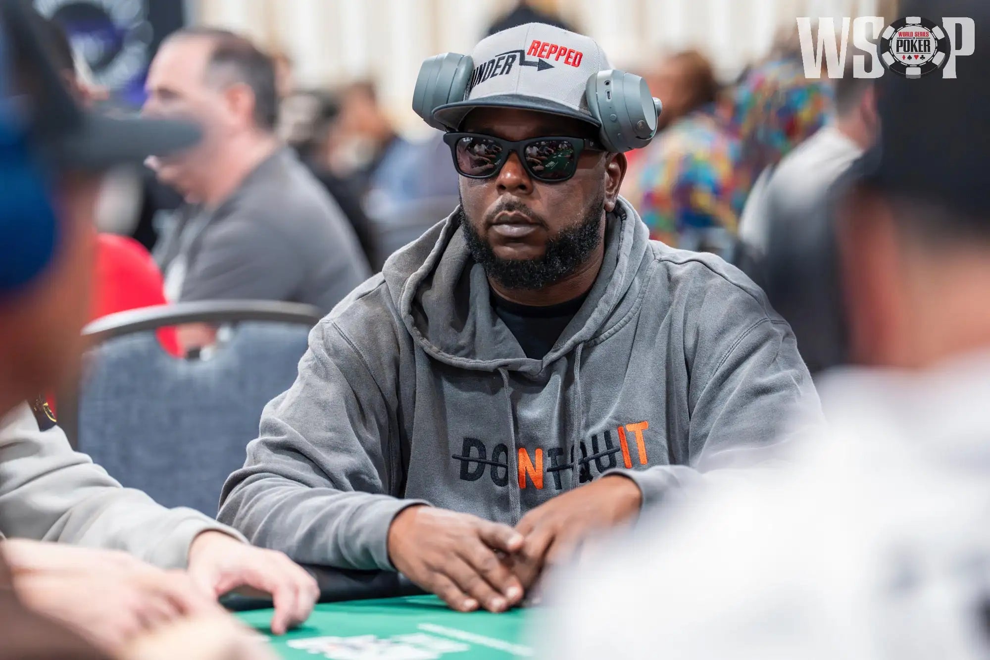 Gray ’repped’ cap with black and red lettering, worn over sunglasses